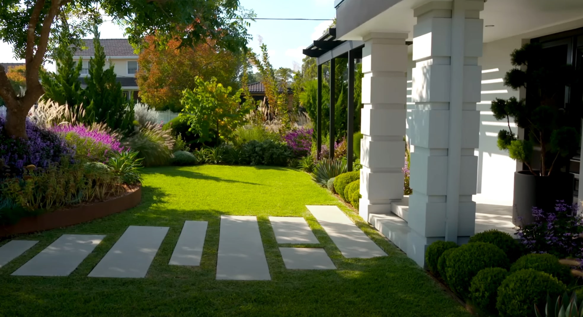 Contemporary front yard landscaping with seasonal color and architectural elements Front yard landscape with colorful perennials, ornamental grasses, and modern hardscaping